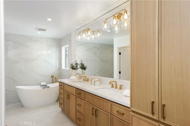 bathroom with double vanity, tile walls, a freestanding tub, a sink, and visible vents