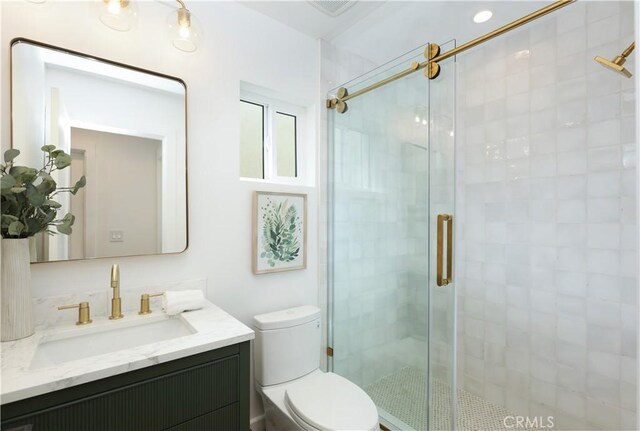 bathroom featuring vanity, toilet, visible vents, and a stall shower