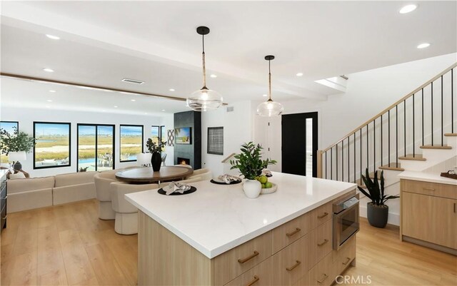 kitchen featuring open floor plan, light brown cabinets, light wood finished floors, and modern cabinets