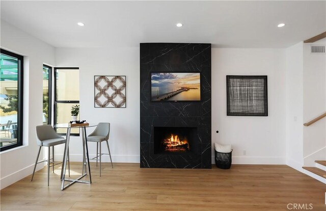 living area featuring visible vents, recessed lighting, light wood-type flooring, and a fireplace
