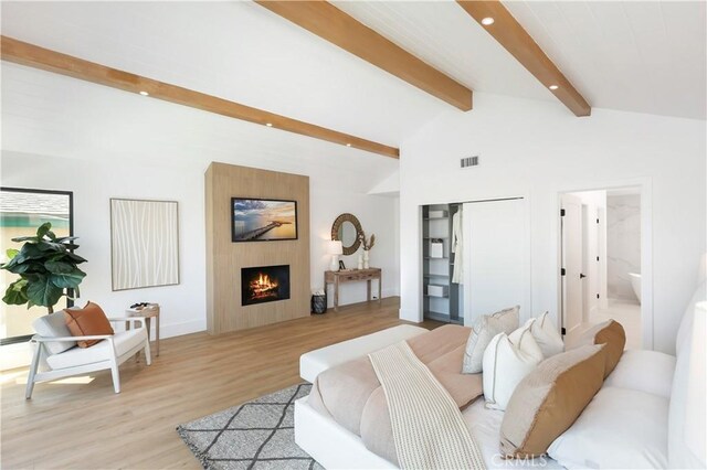 living area featuring recessed lighting, vaulted ceiling with beams, light wood-style floors, a fireplace, and visible vents