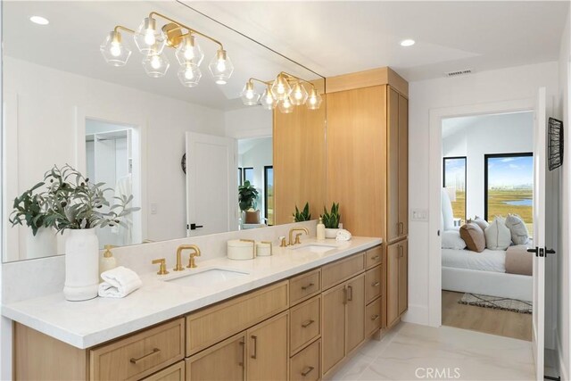 ensuite bathroom featuring visible vents, an inviting chandelier, ensuite bathroom, and a sink