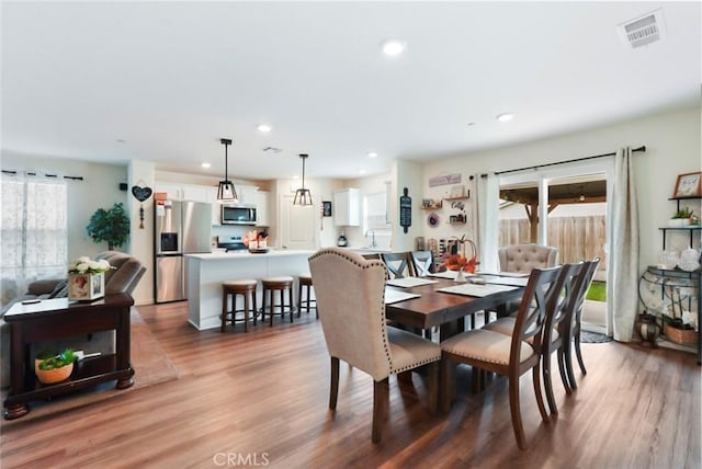 dining room featuring a healthy amount of sunlight, recessed lighting, visible vents, and wood finished floors