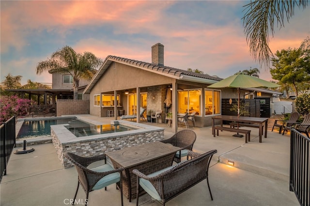 30249 Spray Dr, Canyon Lake, CA 92587 - back of house at dusk featuring a chimney, fence, a patio, stucco siding, and an outdoor pool