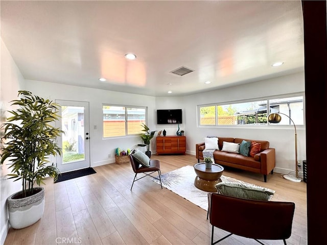 living room with light wood-type flooring, a healthy amount of sunlight, baseboards, and visible vents