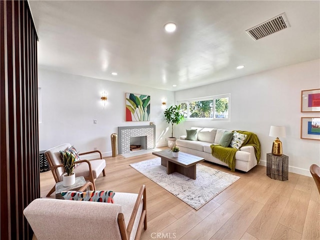 living area featuring visible vents, light wood-style flooring, recessed lighting, and baseboards