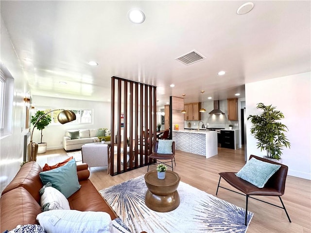 living room with recessed lighting, light wood finished floors, visible vents, and baseboards