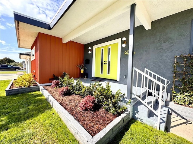 doorway to property with stucco siding and a lawn