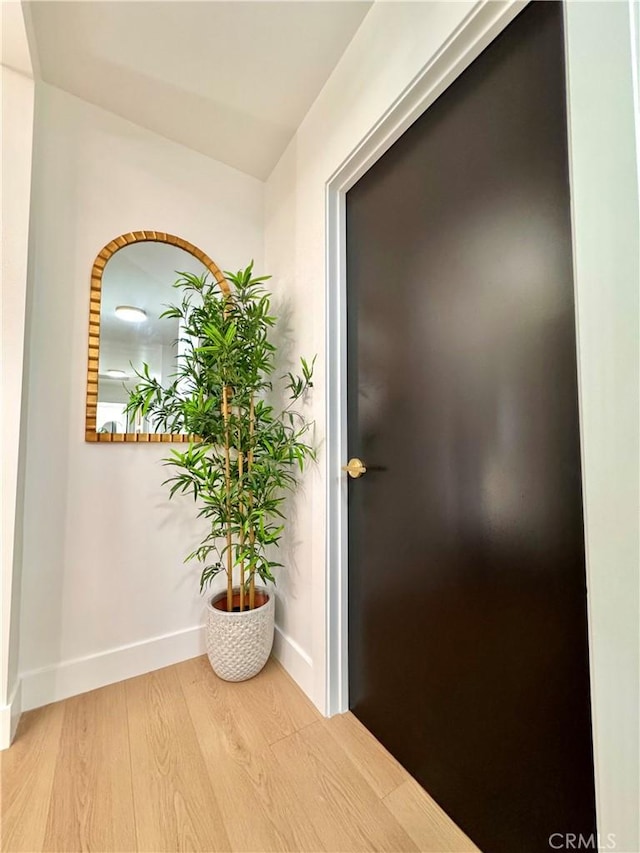corridor with baseboards and wood finished floors