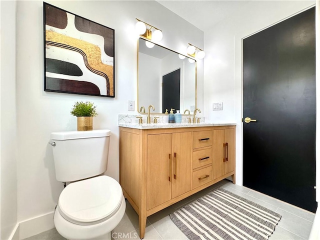 bathroom featuring toilet, tile patterned floors, double vanity, and a sink