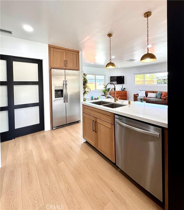 kitchen featuring light wood-style floors, visible vents, appliances with stainless steel finishes, light countertops, and a sink