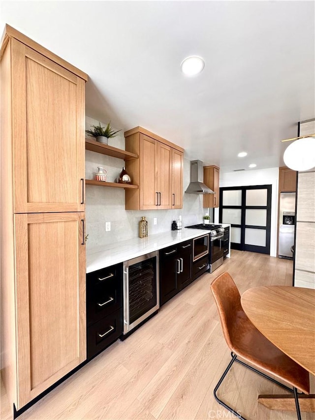 kitchen featuring light wood-type flooring, wall chimney range hood, appliances with stainless steel finishes, light countertops, and beverage cooler