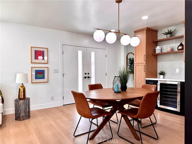 dining room with light wood-style floors, a dry bar, recessed lighting, wine cooler, and baseboards