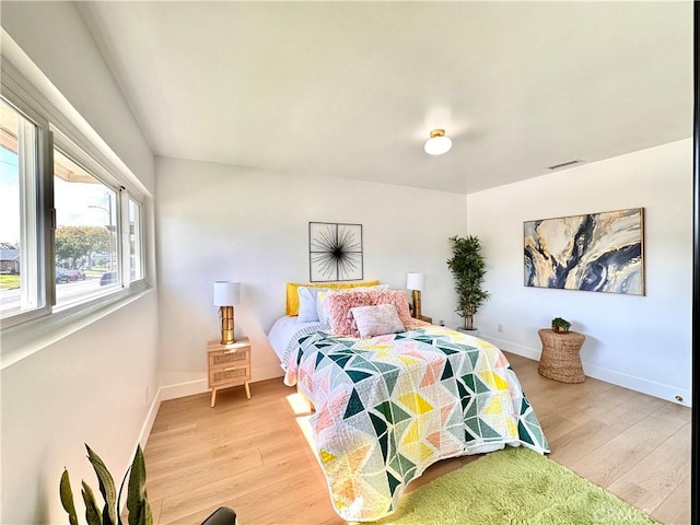bedroom with visible vents, light wood-style flooring, and baseboards