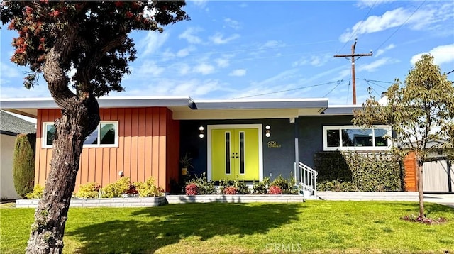 ranch-style house featuring a front yard, french doors, and board and batten siding