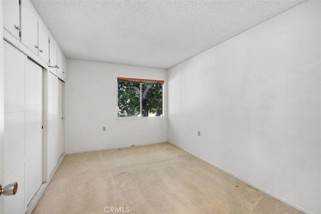 unfurnished bedroom featuring light carpet, a textured ceiling, and a closet