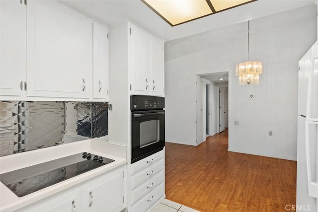 kitchen featuring an inviting chandelier, light wood-style flooring, light countertops, white cabinets, and black appliances