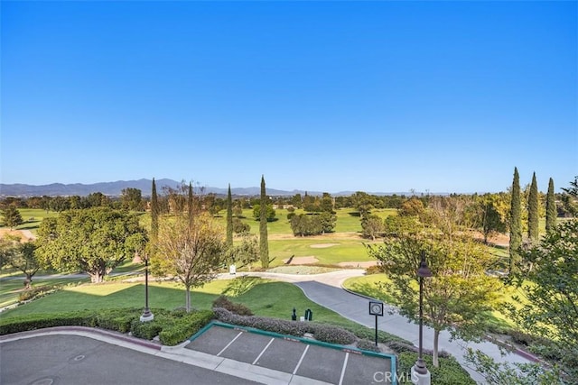 surrounding community featuring a lawn, view of golf course, a mountain view, and uncovered parking