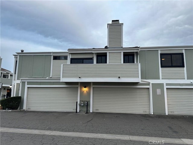 27130 Hidaway Ave Unit 6, Canyon Country, CA 91351 - rear view of house featuring a chimney, a garage, and a balcony
