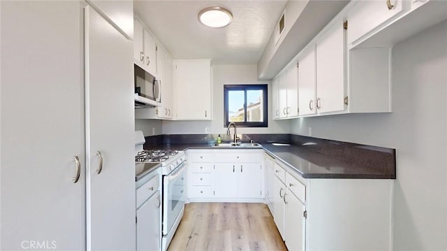 27130 Hidaway Ave Unit 6, Canyon Country, CA 91351 - kitchen featuring white gas range oven, stainless steel microwave, dark countertops, a sink, and white cabinetry