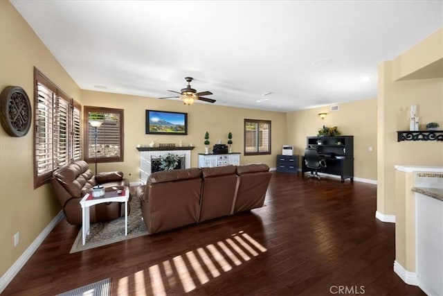 living area with wood finished floors, a fireplace, visible vents, baseboards, and ceiling fan
