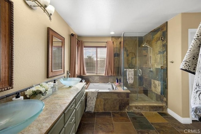 full bathroom with stone tile flooring, a shower stall, a garden tub, and a sink