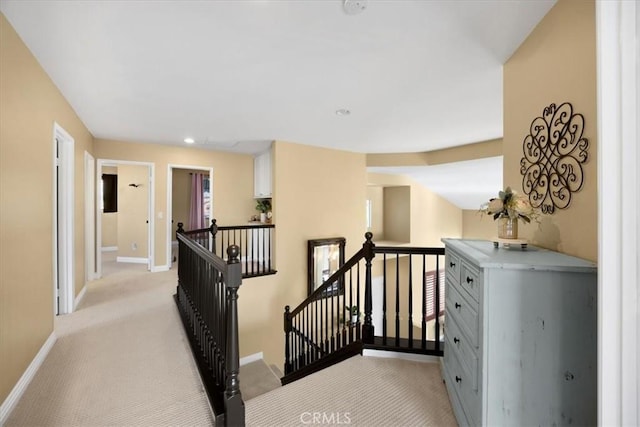 corridor with baseboards, light carpet, and an upstairs landing