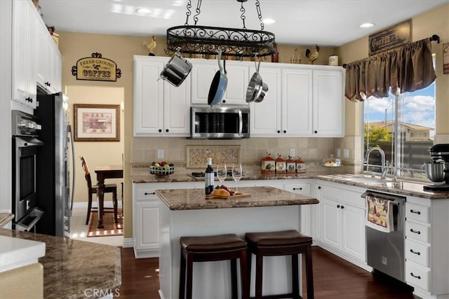 kitchen with white cabinets, stainless steel appliances, tasteful backsplash, and a sink