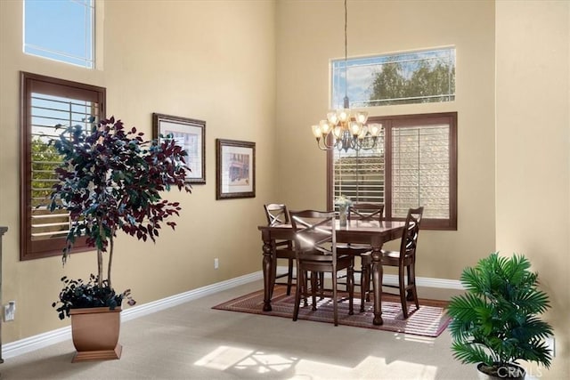 dining room featuring baseboards, a notable chandelier, and a towering ceiling