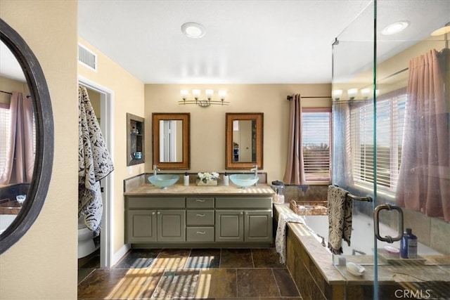 bathroom featuring a sink, double vanity, a garden tub, and visible vents