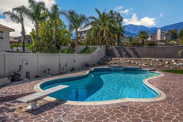 view of pool featuring a mountain view, a diving board, a fenced backyard, a patio area, and a fenced in pool