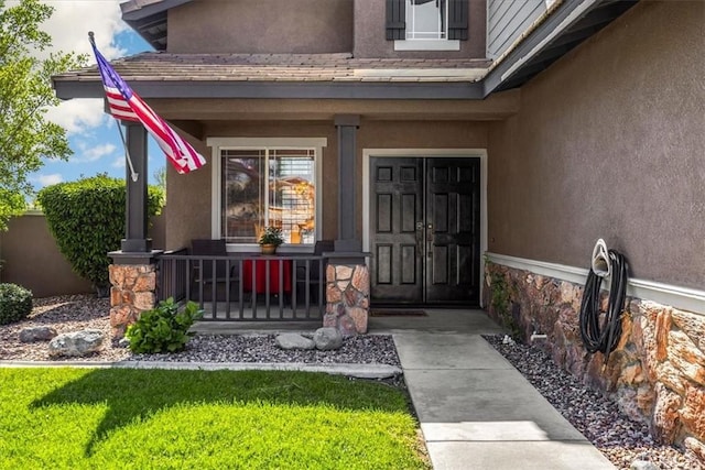 property entrance with a porch and stucco siding