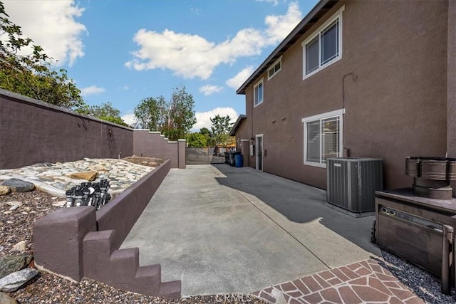 view of side of property featuring cooling unit, a patio area, stucco siding, and fence