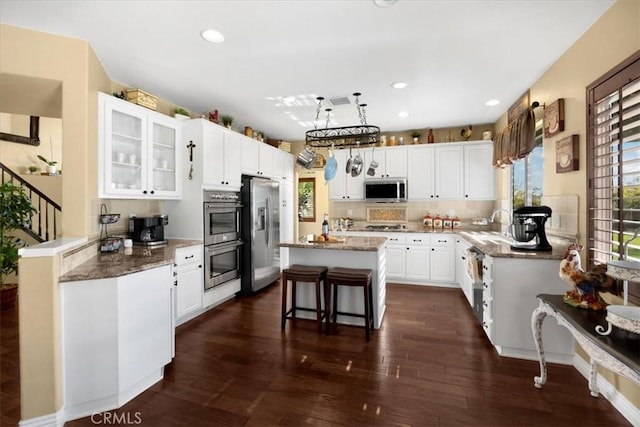kitchen featuring dark wood-style flooring, stainless steel appliances, white cabinetry, and light stone counters