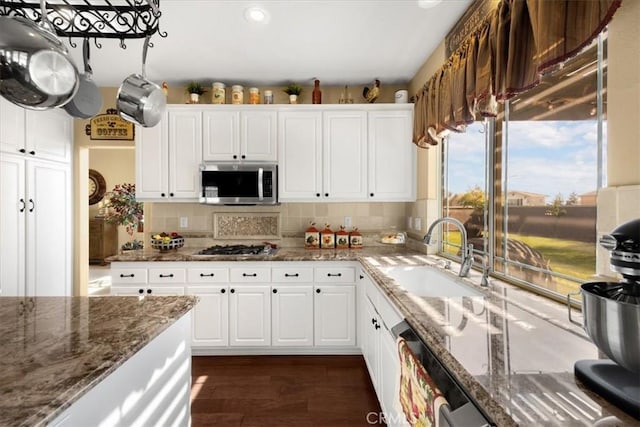 kitchen with a sink, white cabinetry, backsplash, and appliances with stainless steel finishes