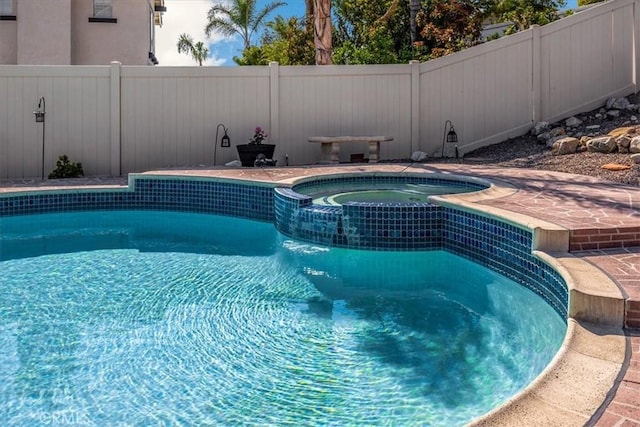 view of pool featuring a pool with connected hot tub and fence