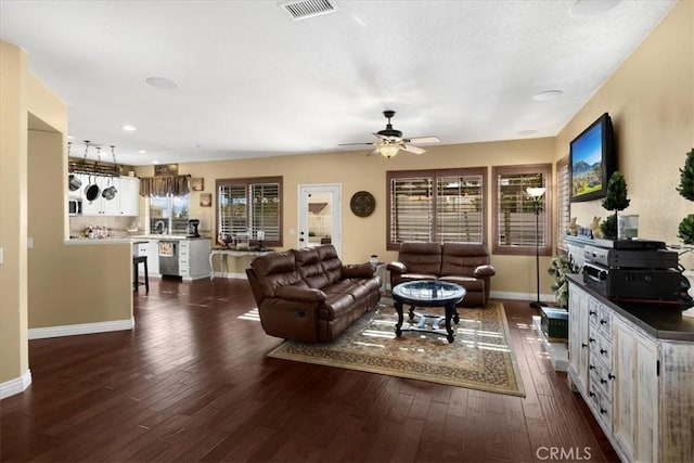 living room featuring dark wood-style flooring, baseboards, and visible vents