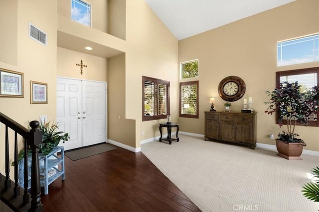 foyer entrance featuring a wealth of natural light, visible vents, baseboards, and a high ceiling
