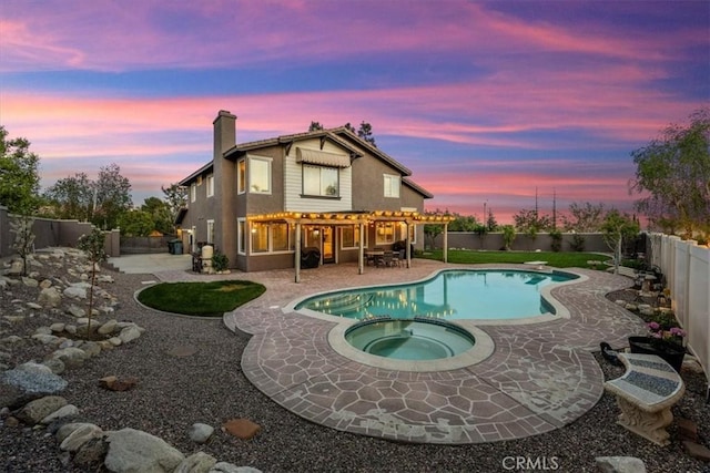 exterior space featuring a pool with connected hot tub, a chimney, a pergola, a fenced backyard, and a patio area