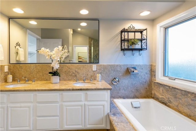 bathroom featuring a wealth of natural light, a bath, and a sink