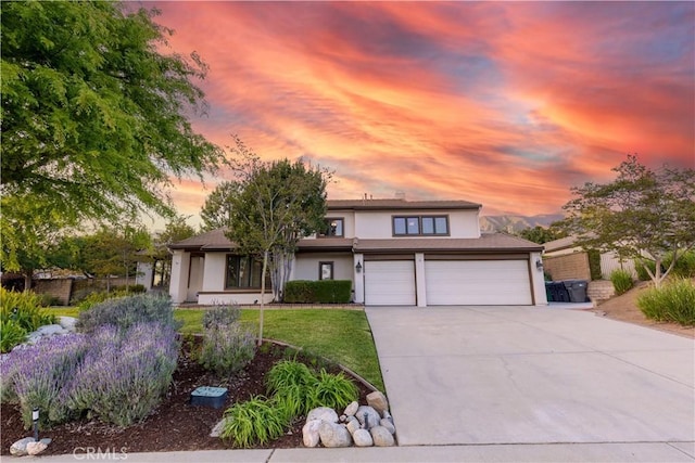 view of front of house featuring a yard, a garage, driveway, and stucco siding