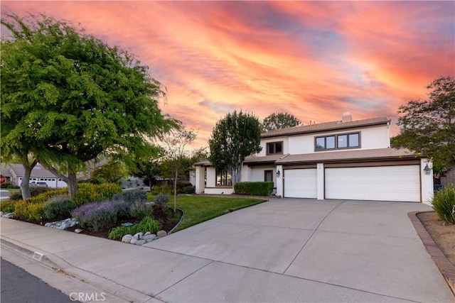 view of front of property with concrete driveway, stucco siding, a garage, and a front lawn