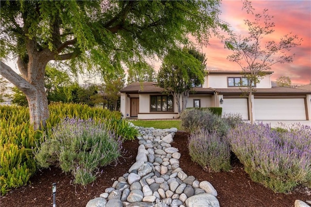 prairie-style home with an attached garage, driveway, and stucco siding