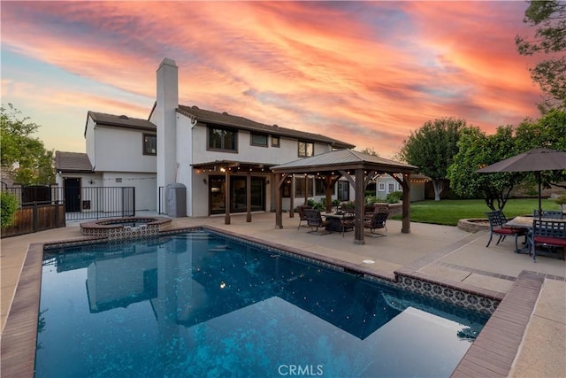 back of property with stucco siding, a chimney, a patio area, fence, and a gazebo