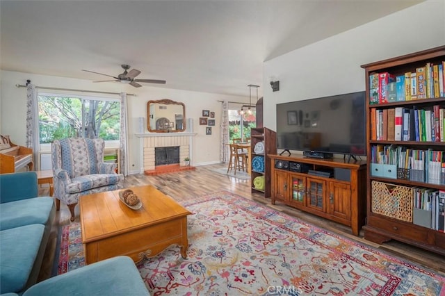 living room with baseboards, a ceiling fan, wood finished floors, and a healthy amount of sunlight