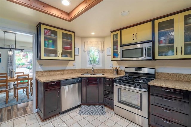 kitchen featuring recessed lighting, light stone counters, light tile patterned floors, a sink, and appliances with stainless steel finishes