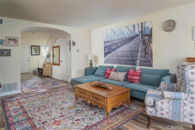 living area with arched walkways, wood finished floors, and visible vents