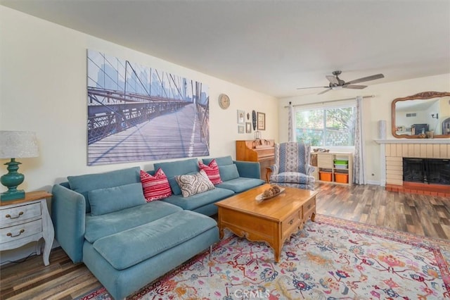 living room with a brick fireplace, wood finished floors, and ceiling fan