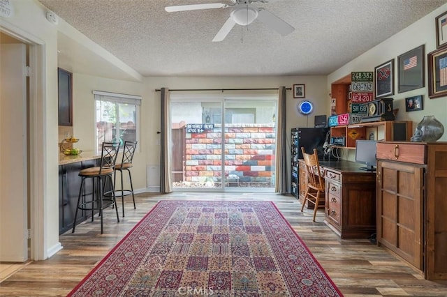 home office with wood finished floors, a textured ceiling, and ceiling fan