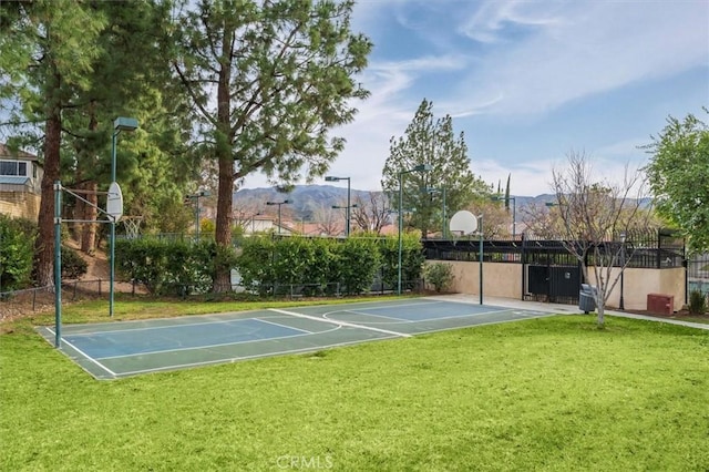 view of basketball court with a lawn, community basketball court, fence, and a mountain view